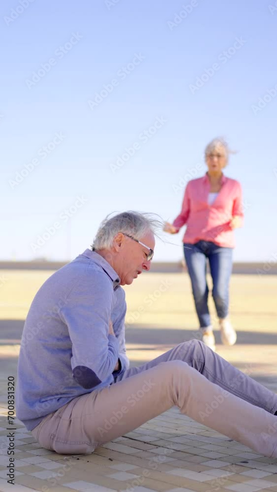 Slow motion video of a senior woman rushing to attend to her husband with chest pain sitting on the beach