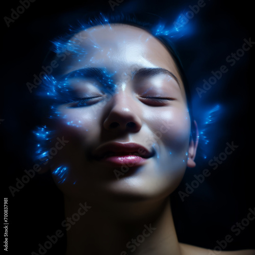 A woman's face, eyes closed, glows blue, her skin bioluminescent under the light.