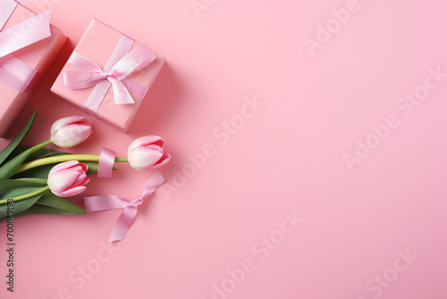 Mother's Day concept. Top view photo of stylish pink giftbox with ribbon bow and bouquet of tulips on isolated pastel pink background with copyspace © Robin