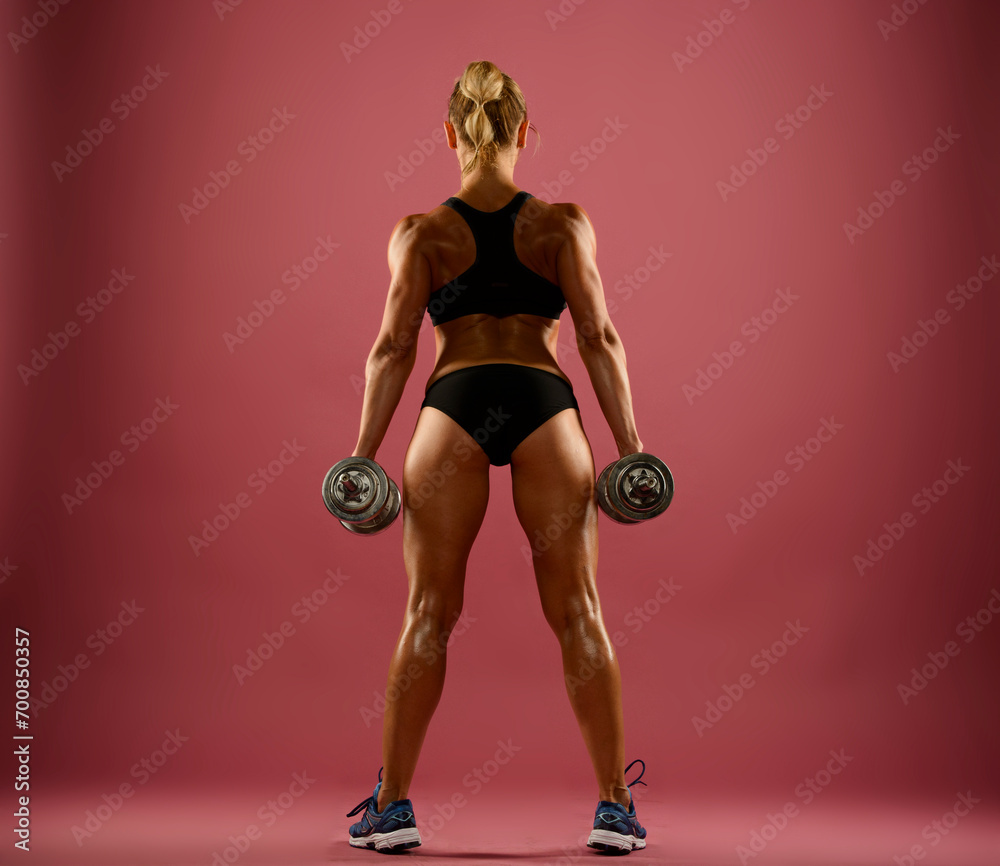 athletic woman with dumbbells from the back in full length