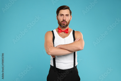 Attractive man with red bow tie posing on light blue background
