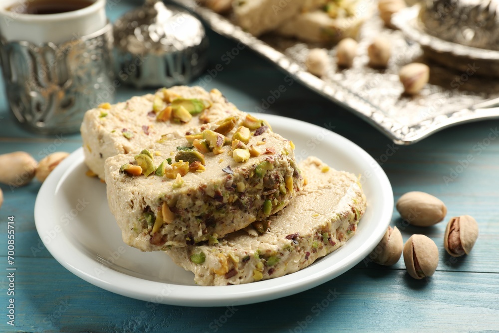 Tasty halva with pistachios on light blue wooden table, closeup