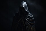 Hooded figure with cape standing in the shadows.