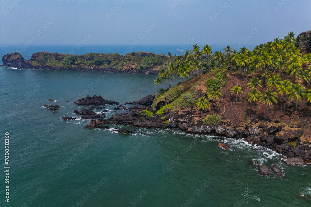 Aerial top view on tropical beach with green palm trees under sunlight Drone view in Goa