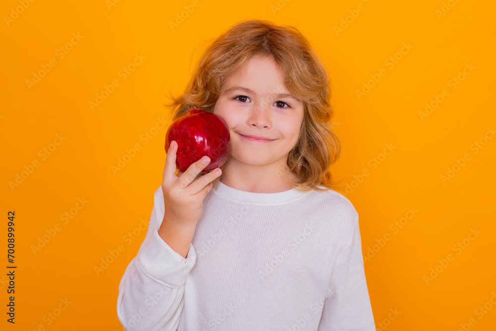 Healthy fruits for kids. Kid hold red pomegranate in studio. Pomegranate fruit. Studio portrait of cute child with pomegranate isolated on yellow background. Healthy fruits for kids. Kid hold red pomegranate in studio. Pomegranate fruit. Studio portrait of cute child with pomegranate isolated on yellow background.