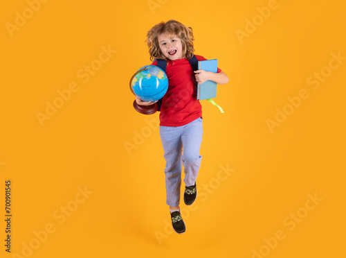 Back to school. Funny child school boy jumping on a yellow studio background.