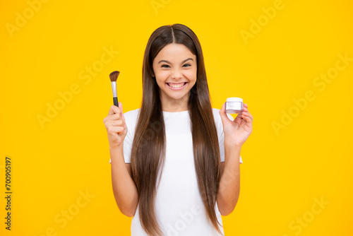 Child teen girl making beauty make up, hold powder and brush. Beautiful teenager applying makeup with powder. Happy teenager portrait. Smiling girl. photo