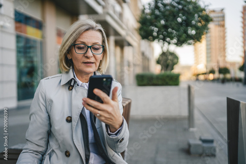 One woman mature female stand in the city outdoor use mobile phone