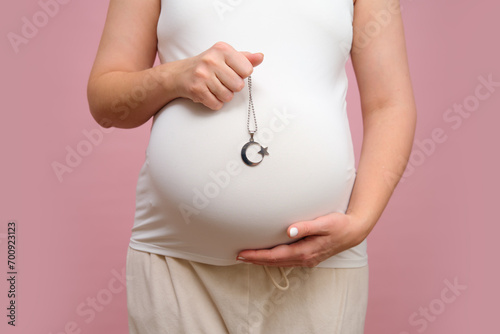 Wallpaper Mural Pregnant woman holding religious muslim symbol in hand, studio pink background Torontodigital.ca