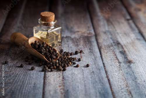 Dry organic Sheetal Chini (Piper cubeba) seeds, in a wooden scoop along with its essential oil. photo