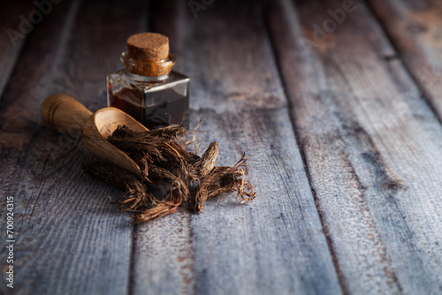 Dry organic Jatamansi (Nardostachys jatamansi) roots, in a wooden scoop along with its essential oil. photo