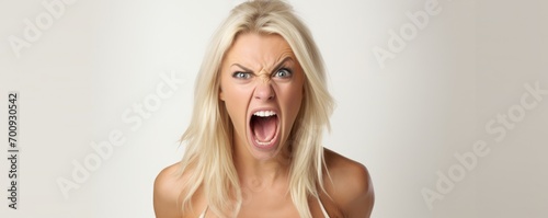 Angry young blonde woman screaming on white background. Anger expression concept. photo
