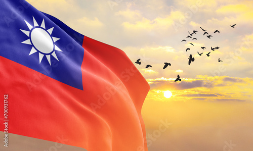 Waving flag of Taiwan against the background of a sunset or sunrise. Taiwan flag for Independence Day. The symbol of the state on wavy fabric.