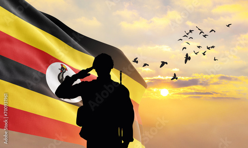 Silhouette of a soldier with the Uganda flag stands against the background of a sunset or sunrise. Concept of national holidays. Commemoration Day. photo