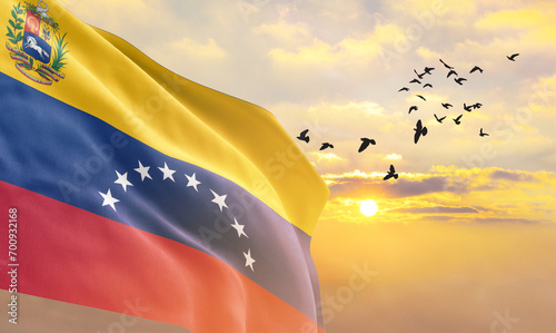 Waving flag of Venezuela against the background of a sunset or sunrise. Venezuela flag for Independence Day. The symbol of the state on wavy fabric. photo