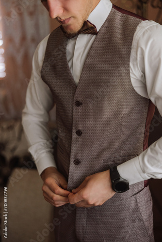 The groom fastens a button on his vest at the groom's morning gatherings. Groom wedding preparation.