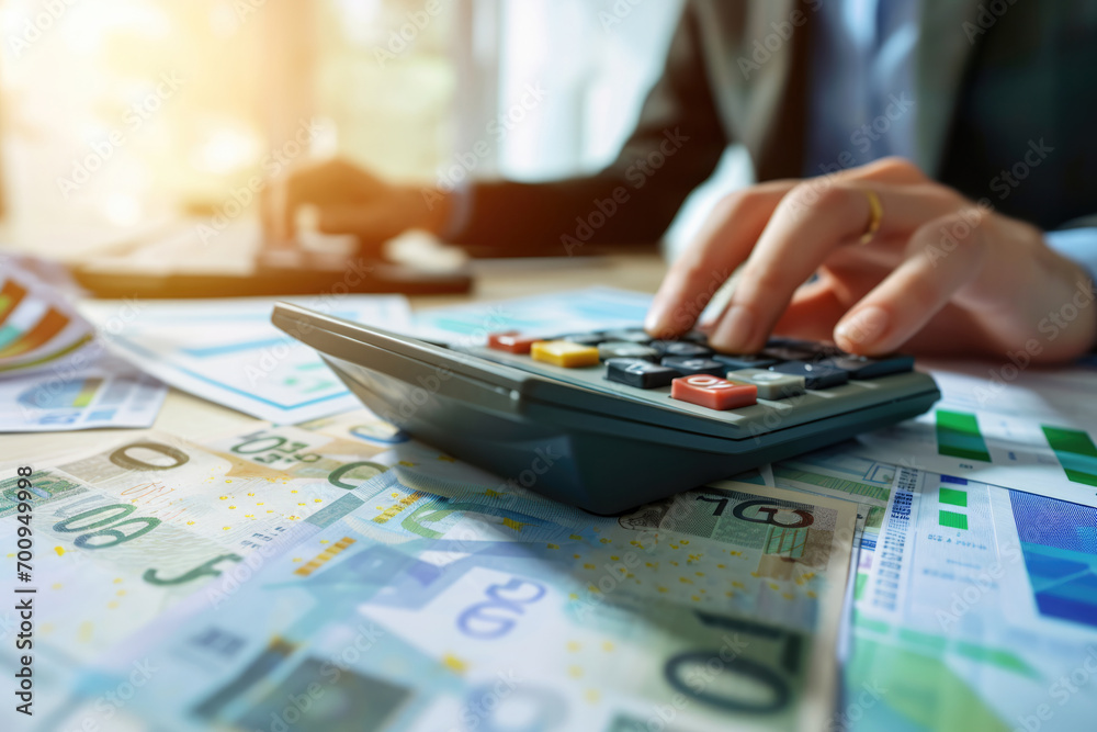 Fototapeta premium The hand doing the calculations with a calculator on money notes, an accountant financier