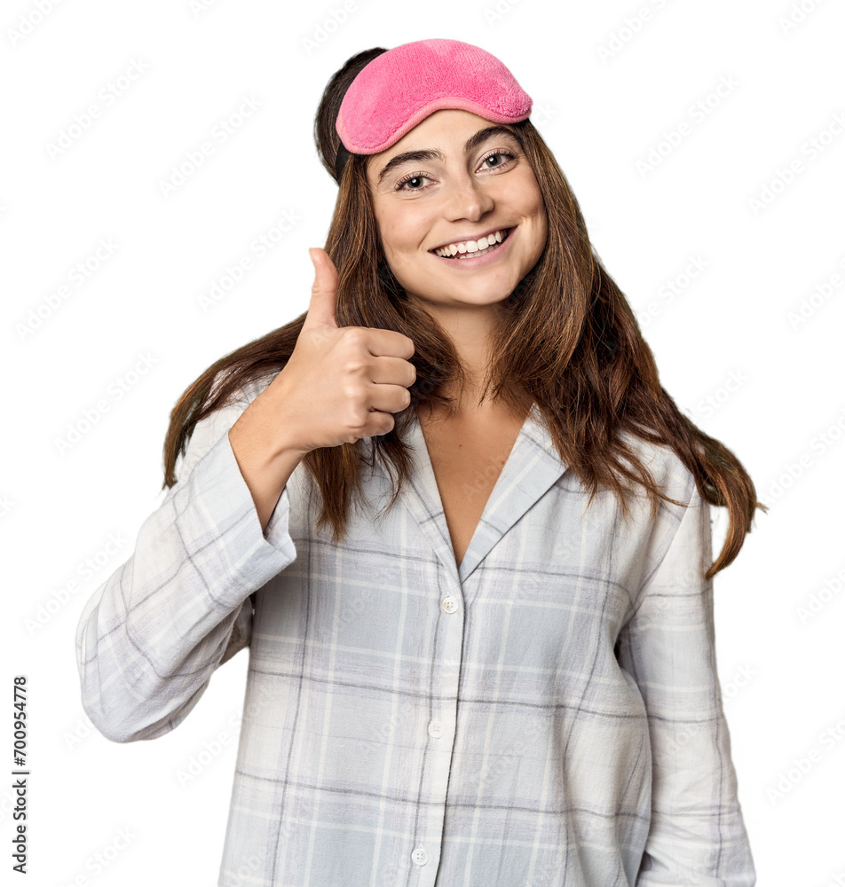 Young Caucasian woman in pajamas with mask smiling and raising thumb up Young Caucasian woman in pajamas with mask smiling and raising thumb up
