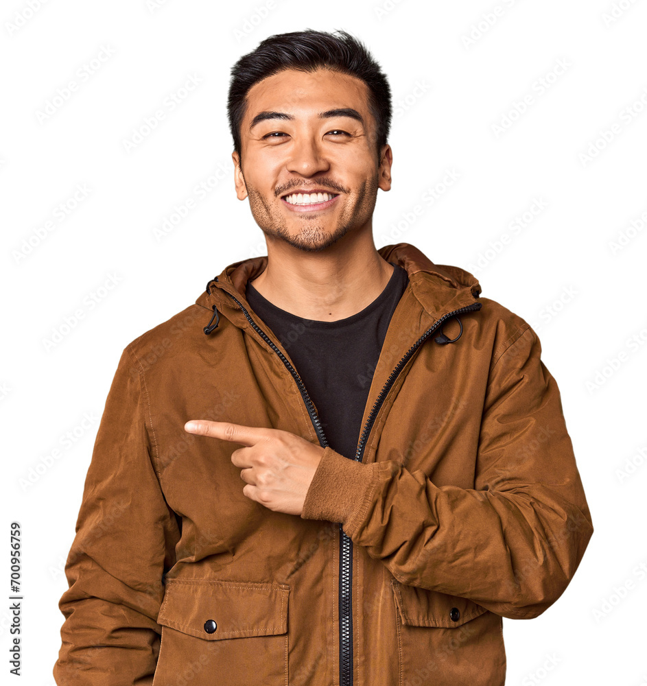 Young Chinese man in studio background smiling and pointing aside, showing something at blank space. Young Chinese man in studio background smiling and pointing aside, showing something at blank space.