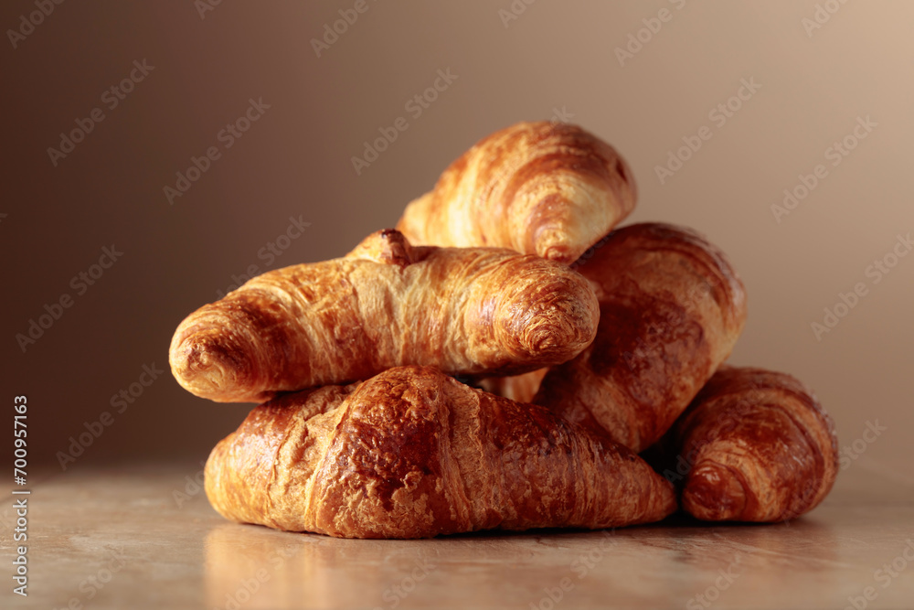 Fototapeta premium Freshly baked croissants on a beige ceramic table.