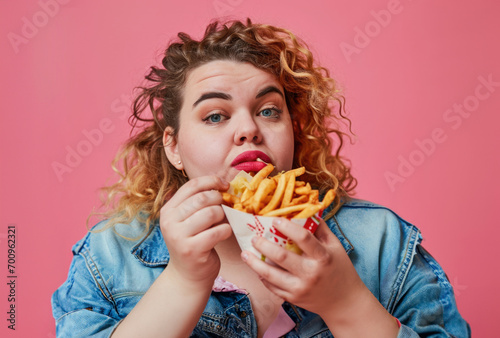 Very fat girl on pink background with fast food in her hands  the harm of food