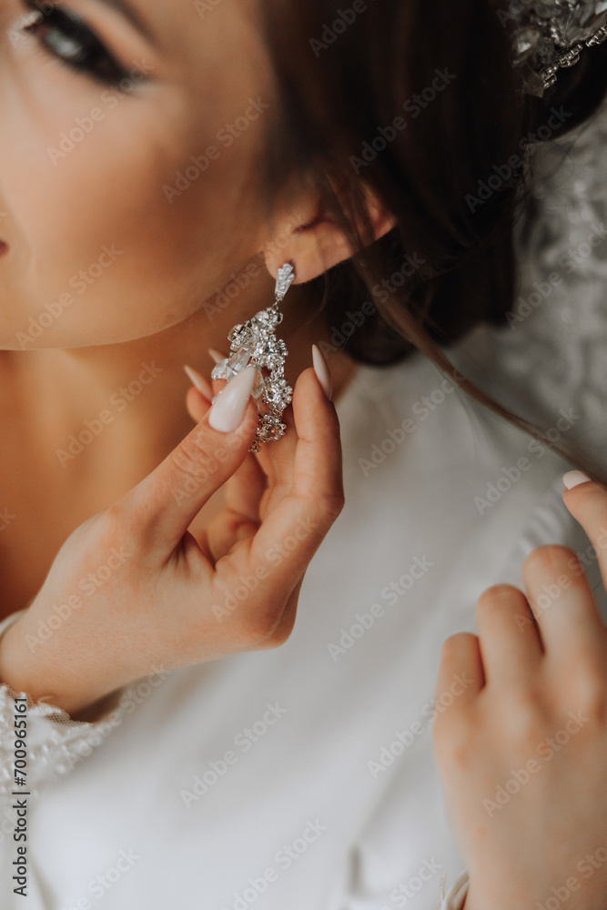 close-up of a beautiful girl in soft satin underwear wearing earrings. Wedding morning of the bride. Advertising decorations. A woman goes on a date.