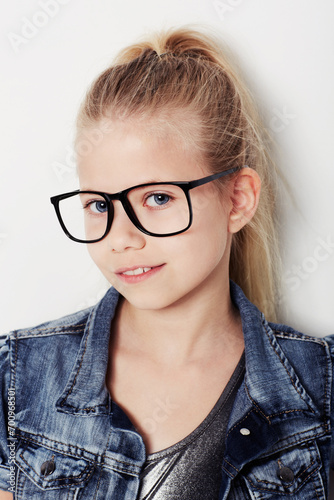 Child, portrait and cool fashion glasses in studio, frame and confident by white background. Female person, girl and casual clothing or style by backdrop, kid and denim jacket pride for eyesight test