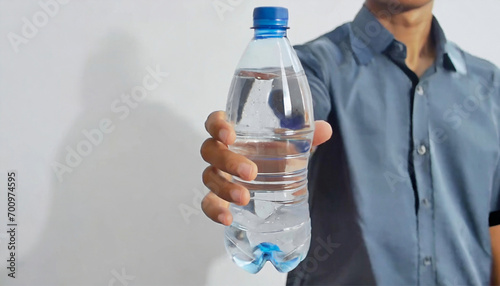 a man's hand holds a clear mineral bottle with a splash of water