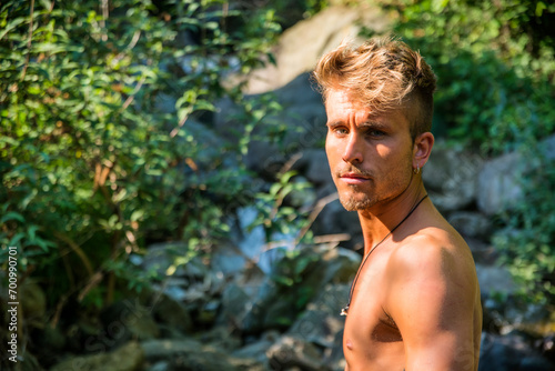 Shirtless blond young man in nature