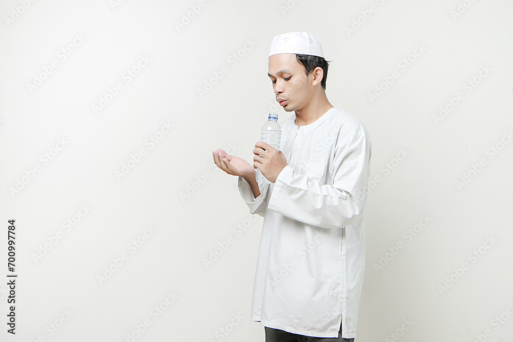 asian muslim man holding water bottle and pray. holding palm face up. People religious Islam lifestyle concept. celebration Ramadan and ied Mubarak. on isolated background.