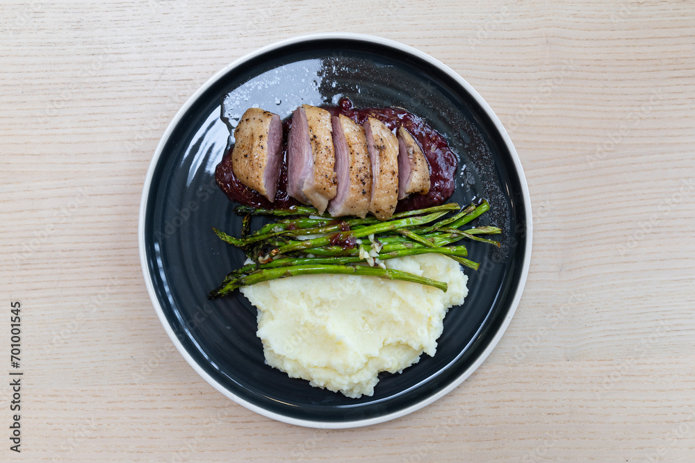 A plate of duck breast, asparagus, and mash potato.