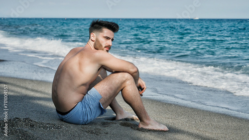 Young man sitting on a beach alone and lonely