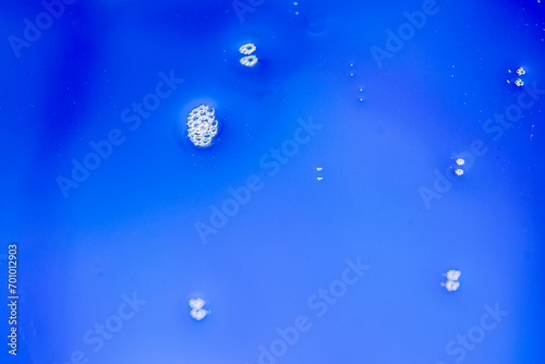 Photograph of water droplets clumping together in groups. The background is blue. Take photos with a macro or close-up lens.