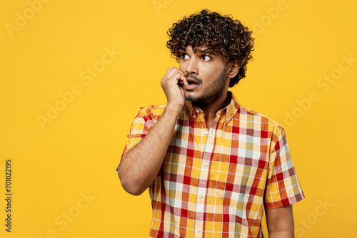Young minded pensive confused puzzled Indian man wears shirt casual clothes biting nails fingers look aside on area mock up isolated on plain yellow color background studio portrait Lifestyle concept photo