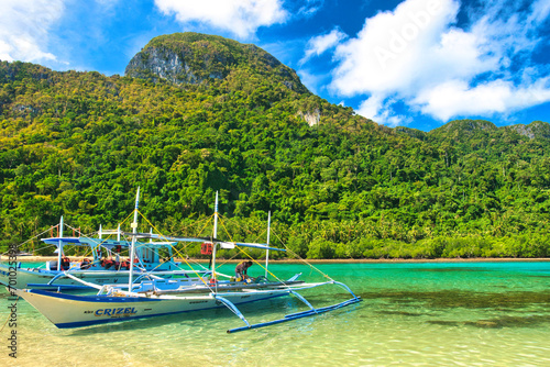 PALAWAN, PHILIPPINES - DECEMBER 21, 2023: Local traditional outrigger tour boat with tropical islands in El Nido on Palawan Island in the Philippines. 6 million tourists visited Philippines in 2016.