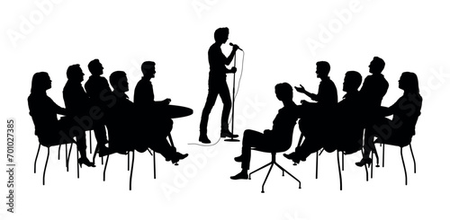 Man stand up comedian performs on stage in front of audience silhouettes. photo