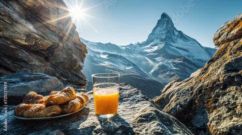 A refreshing morning scene with a glass of orange juice and pastries set against the majestic backdrop of the matterhorn peak under a clear blue sky 