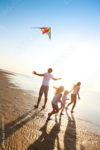 Happy young family with flying a kite on the beach photo