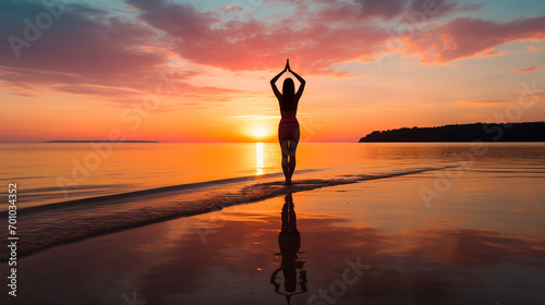 person practicing yoga on a beach at sunset