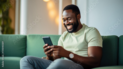 Happy man using a smartphone while comfortably seated on a couch