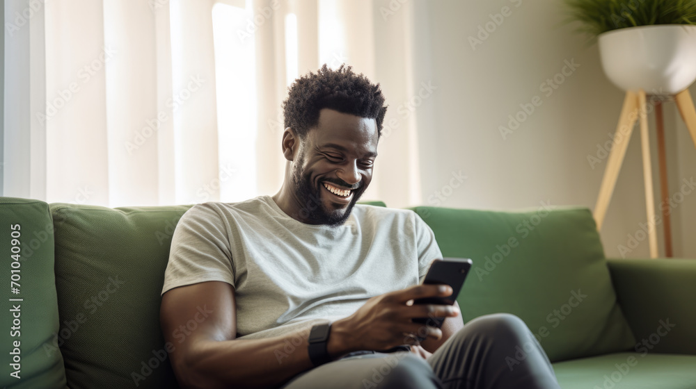 Happy man using a smartphone while comfortably seated on a couch Happy man using a smartphone while comfortably seated on a couch
