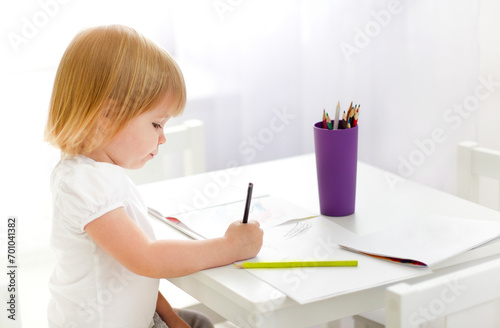 Smart cute girl drawing with pencil at home