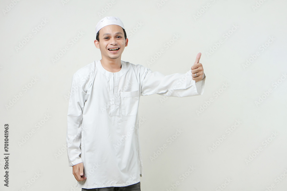 Asian Muslim give thumb up gesture on isolated background. People religious Islamic lifestyle concept Asian Muslim give thumb up gesture on isolated background. People religious Islamic lifestyle concept