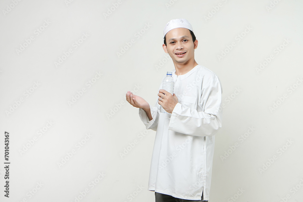 asian muslim man holding water bottle and make pray hand gesture. People religious Islam lifestyle concept. celebration Ramadan and ied Mubarak. on isolated background.