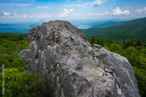A giant granite boulder on a mountaintop above green meadows in Grayson Highlands State Park, Virginia