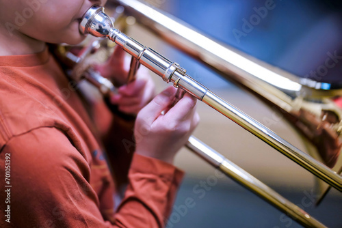 Student boy playing and practicing trombone during music class. Music instrument and art education background.