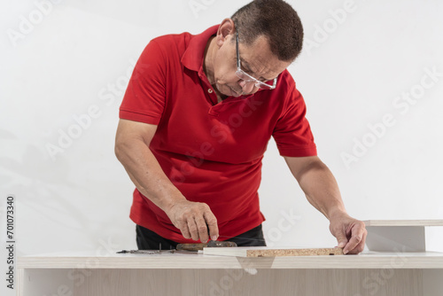 Elderly Man Precisely Measuring Wood for Furniture