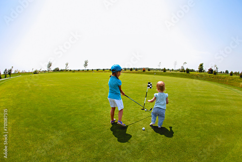 Kids playing golf game on green meadow © Dasha Petrenko
