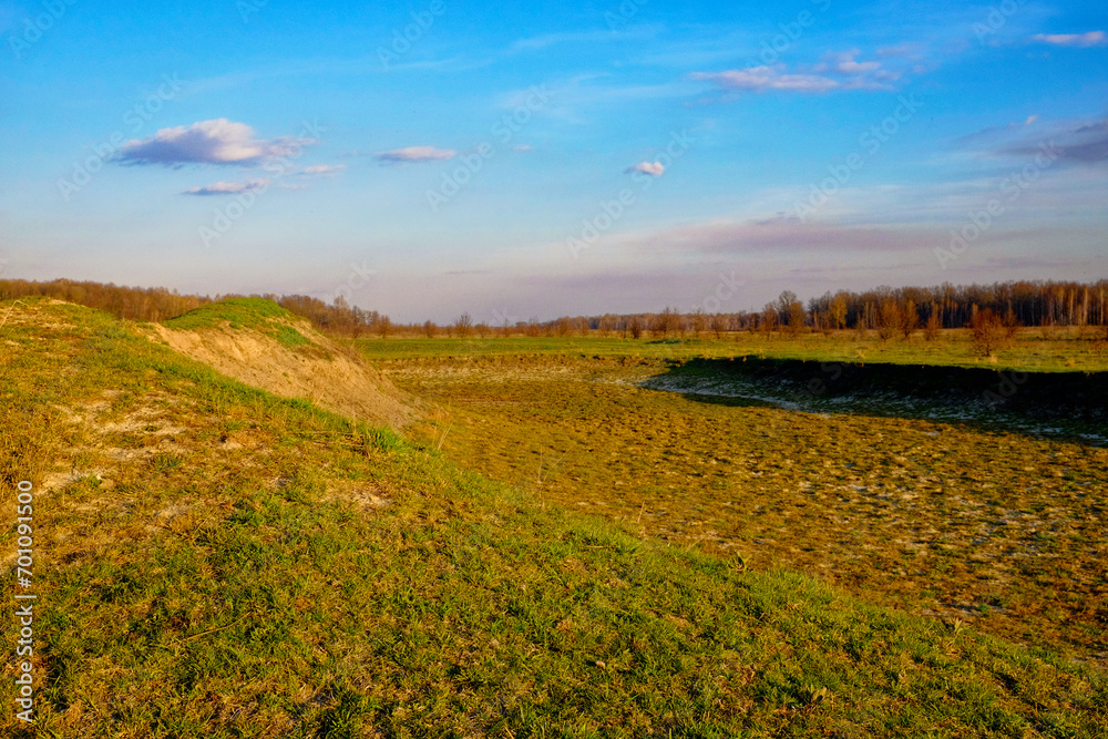 Obraz premium The dry pond landscape is depicted in this photograph, where the exposed bottom unveils the impact of drought.