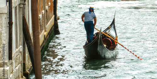 Foto Venetian gondolier punting gondola through green canal waters of Venice